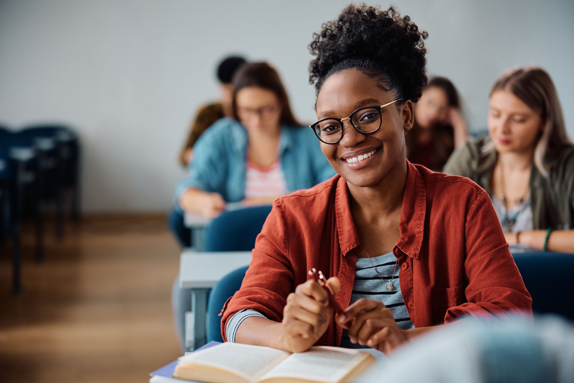 Happy black female student during a class in lecture hall looking at camera.